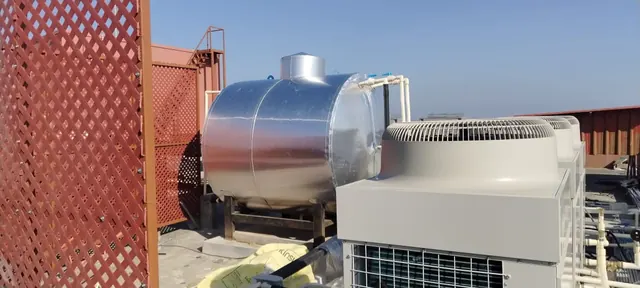Insulated hot water tank beside a large air-source heat pump