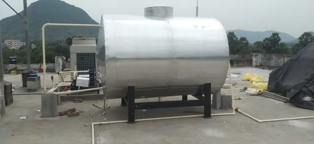 Insulated hot water tank and heat pump on an open rooftop with hills behind