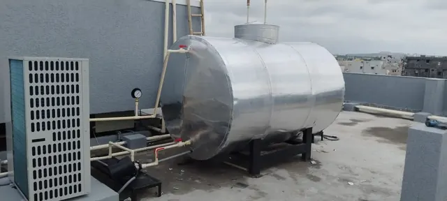 Air-source heat pump next to an insulated hot water tank on a rooftop