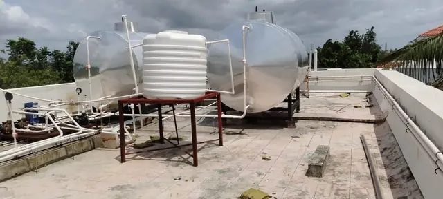 Twin insulated storage tanks on a rooftop with a cold water tank between them